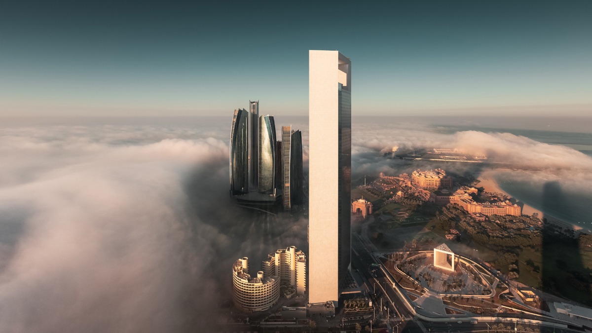 Abu Dhabi skyline rising above a layer of morning fog at sunrise, with landmark towers catching the early light