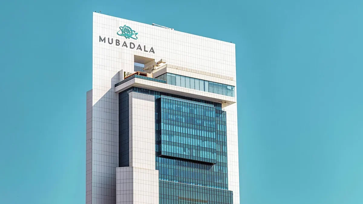 The Mubadala headquarters tower in Abu Dhabi, with the company's logo mounted near the top of the building against a clear sky