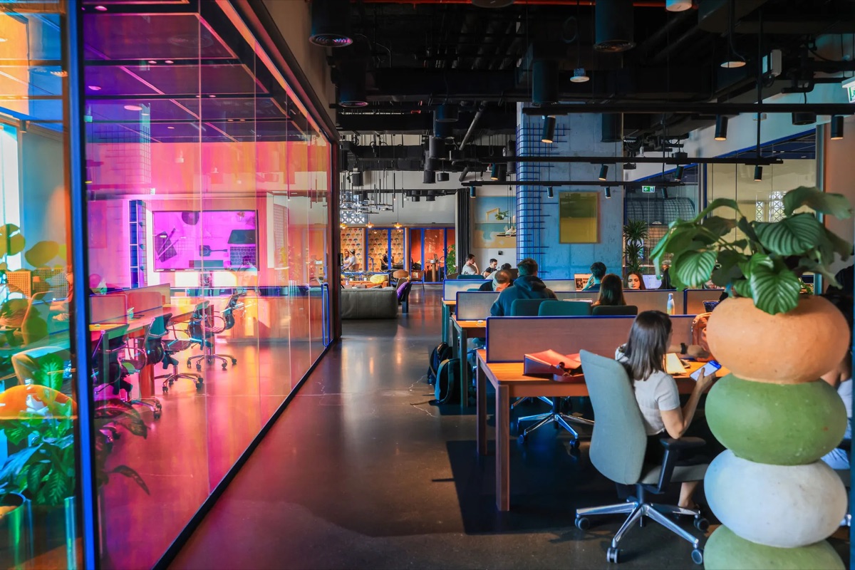 A modern, colourful coworking space in Dubai filled with people working at desks, reflecting the region's growing startup and finance scene