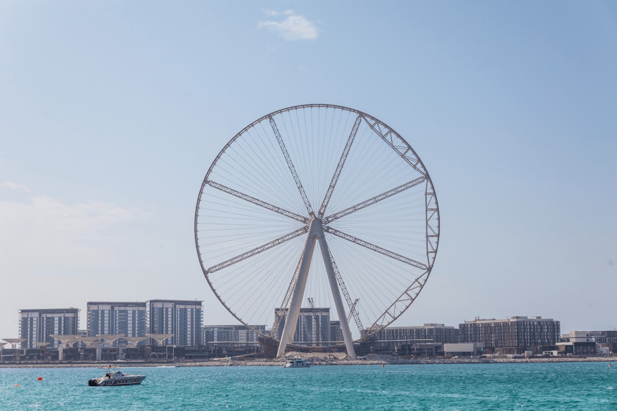 Ain Dubai observation wheel rising above Bluewaters Island with the JBR skyline and turquoise Gulf waters in the foreground